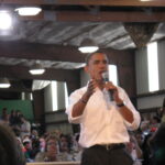 Barack Obama speaking with a microphone at a town hall event