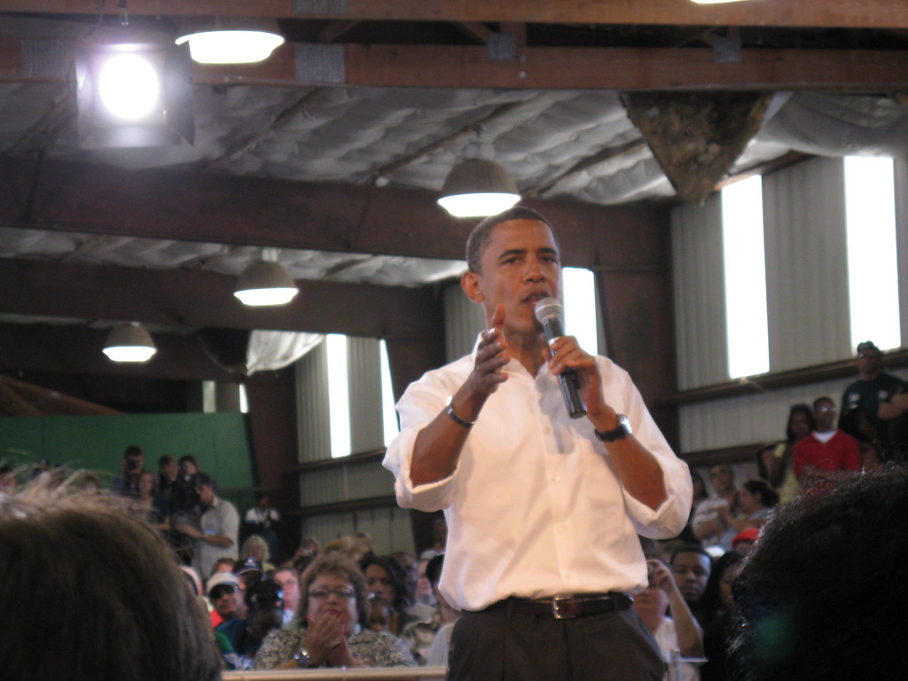 Barack Obama speaking with a microphone at a town hall event
