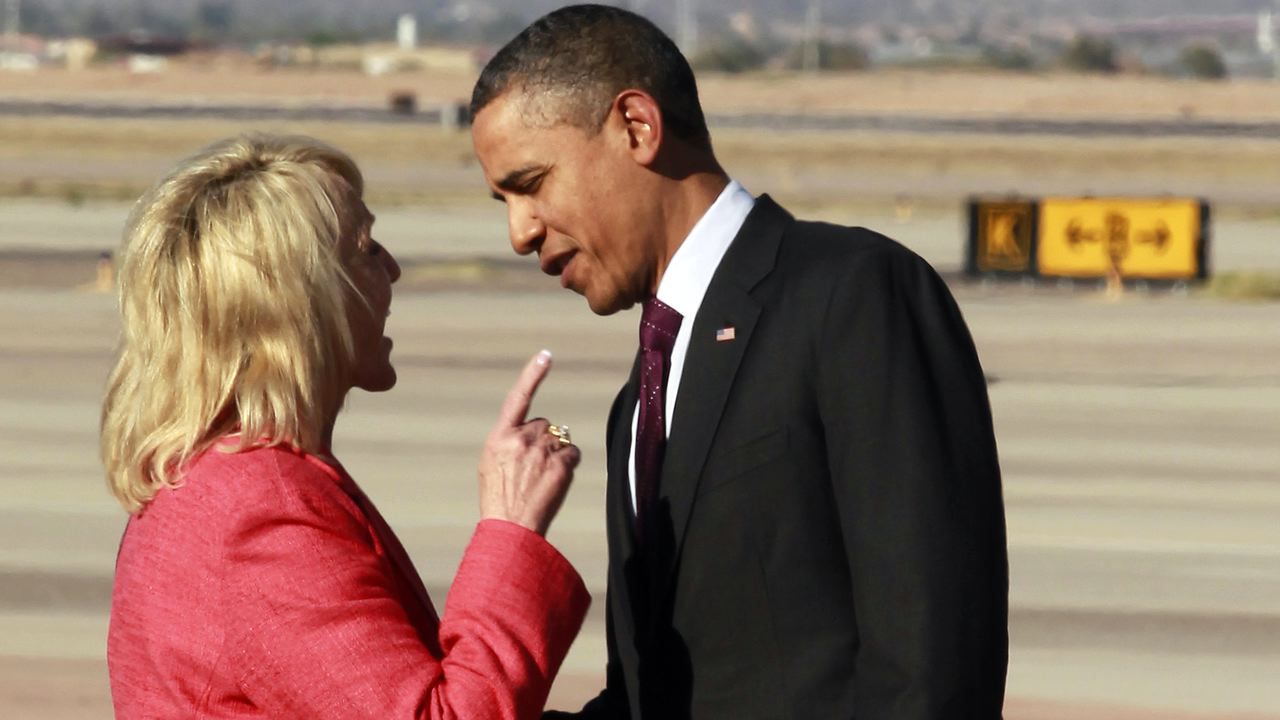 President Obama and Arizona Governor Jan Brewer speaking face to face on an airport tarmac, Brewer pointing a finger toward him